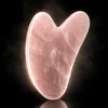 Gua sha en quartz rose – lumière dorée Gua sha en quartz rose sur fond sombre avec halo lumineux doré