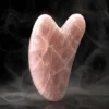 Gua sha en quartz rose – texture naturelle Gua sha en quartz rose avec détails de la pierre naturelle sur fond sombre