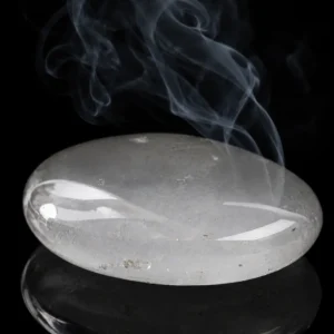 Galet de quartz transparent poli sur fond noir avec fumée