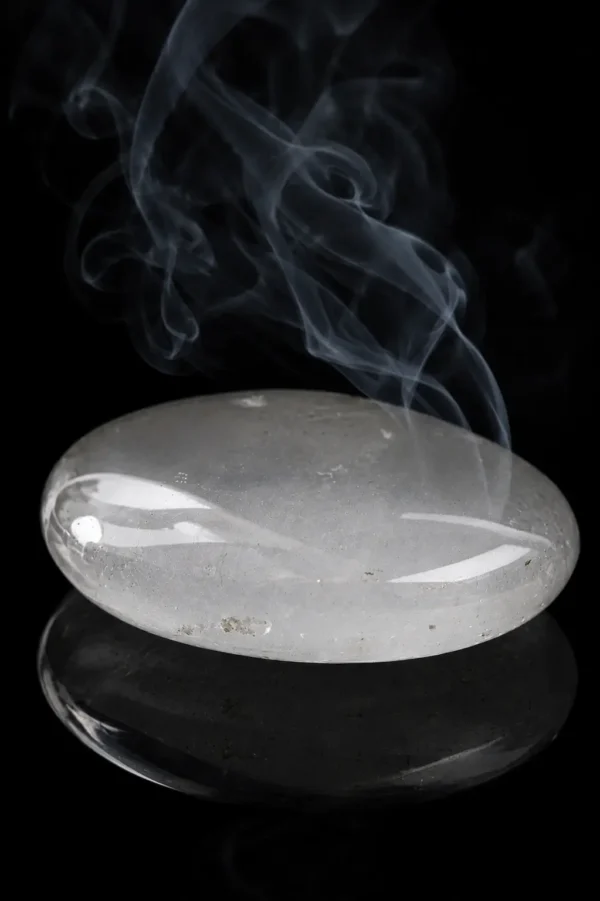 Quartz transparent – galet poli Galet de quartz transparent poli sur fond noir avec fumée